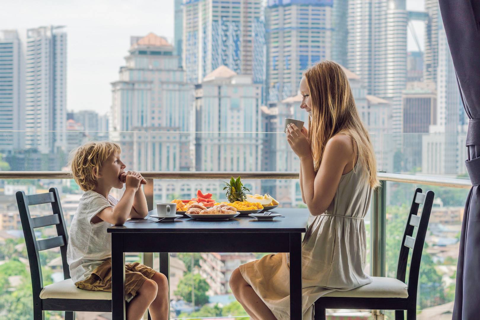 Nastoletnia siostra z młodszym bratem jedzą śniadanie na balkonie w mieście